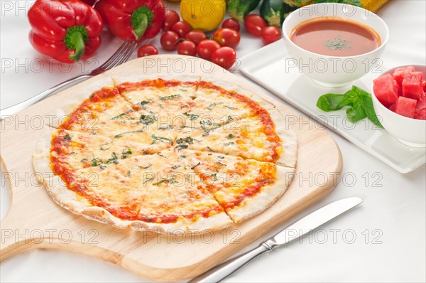 Italian original thin crust pizza Margherita with gazpacho soup and watermelon on side