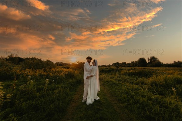 Loving couple of newlyweds at sunset in the field