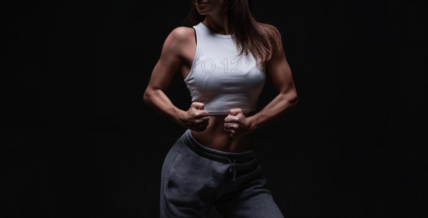 Athletic fitness woman posing in the studio on a dark background. Photo of an attractive woman in fashionable sportswear. Sports and healthy lifestyle. Mixed media