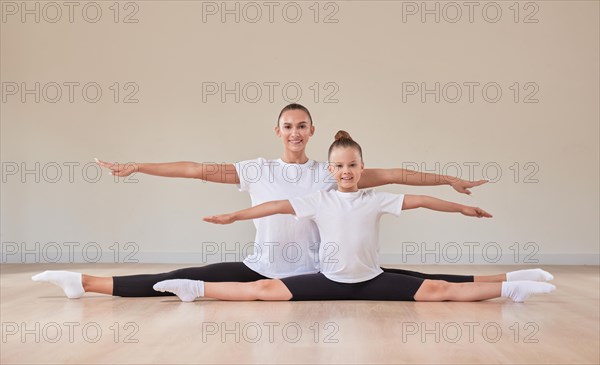Beautiful female teacher and a little girl are sitting in the splits in a gymnastics class. The concept of education