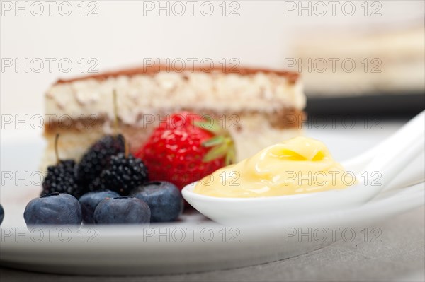 Classic Italian tiramisu dessert with berries and custartd pastry cream on side