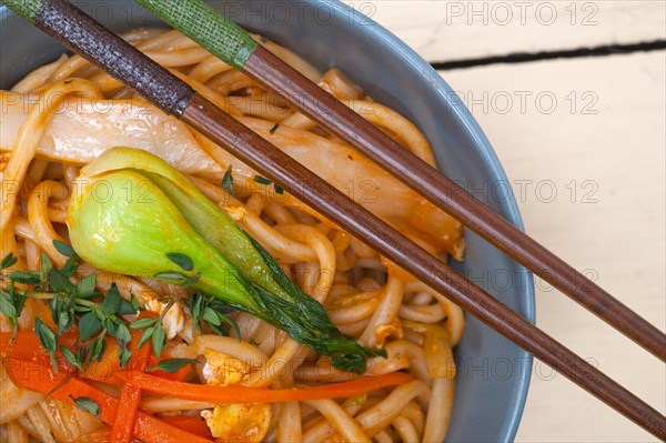 Hand pulled stretched Chinese ramen noodles on a bowl with chopstick