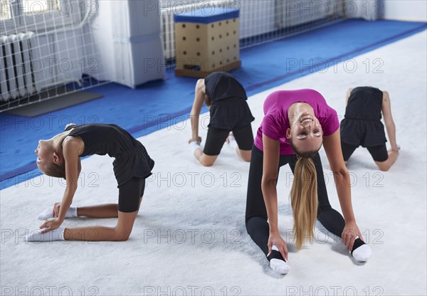 Training in the gym class. A group of children under the guidance of a coach perform exercises. Gymnastics concept. Mixed media