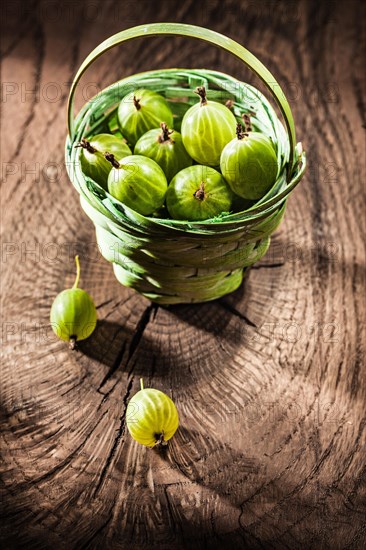 Gooseberries in basket on vintage wooden board