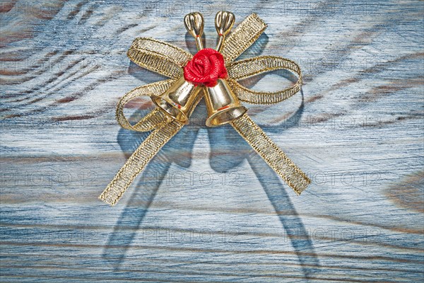 Golden Christmas knot with bell on wooden board holidays concept