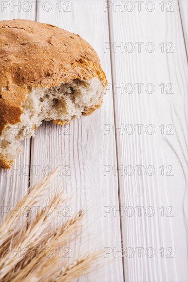Sliced bread and ears of wheat on white-painted wooden boards with copyspace food and drink concept