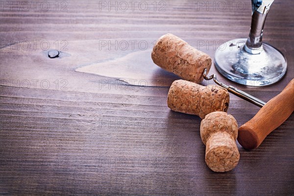 Corkscrew twisted in cork of champagne and wine glass on vintage wooden board very close up with copyspace alcohol concept