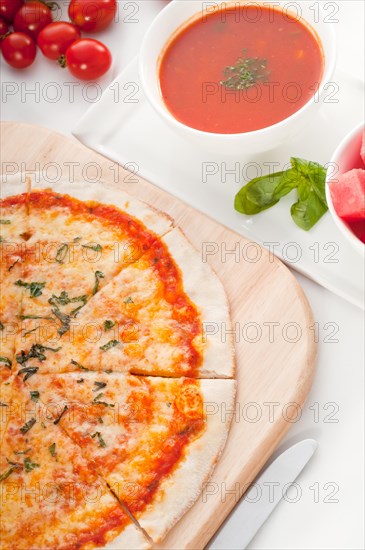 Italian original thin crust pizza Margherita with gazpacho soup and watermelon on side