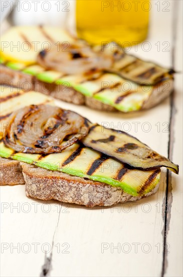 Grilled vegetables on rustic bread over wood table