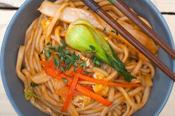 Hand pulled stretched Chinese ramen noodles on a bowl with chopstick