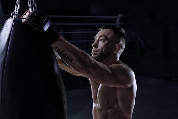 Kickboxer hooks a punching bag to a rope. Sports training. The concept of mixed martial arts. MMA