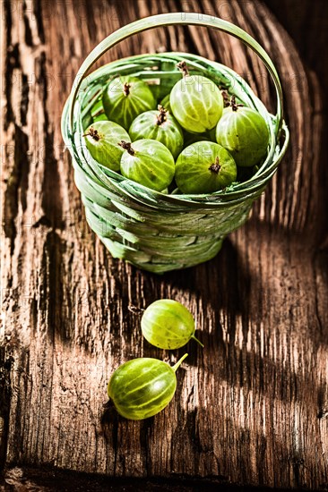 Gooseberries in basket on obsolete wooden board