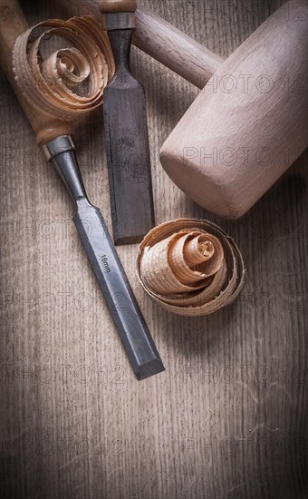 Wooden mallet curled up shavings flat chisels on wood board construction concept