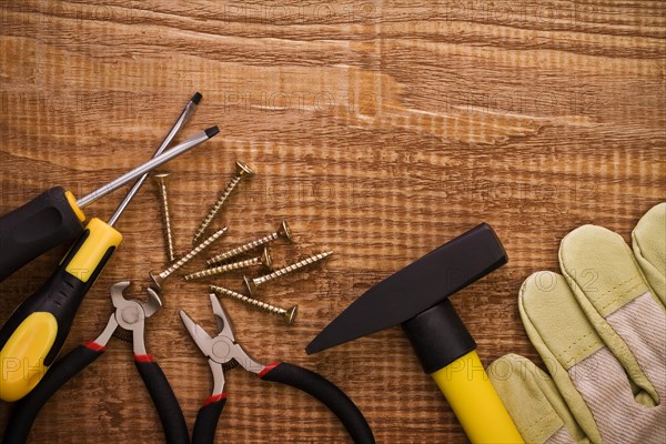 Hamer pliers screwdriver and gloves on woodn board