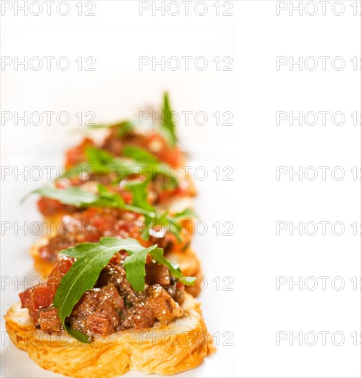 Fresh tipycal italian bruschetta with tomato and arugula on top