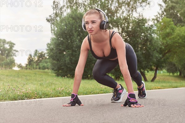 Image of a girl in headphones who stands in a lower position before starting to run. The concept of a healthy lifestyle. Mixed media