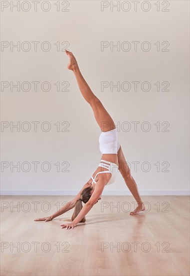 Flexible woman is training in a light studio. The concept of gymnastics