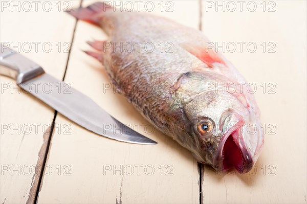 Fresh whole raw fish on a wooden table ready to cook