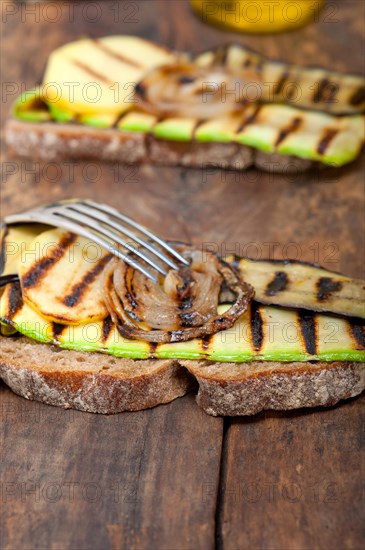 Grilled vegetables on rustic bread over wood table