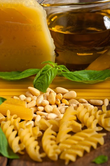 Italian basil pesto ingredients and raw pasta over old wood macro