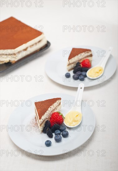 Classic Italian tiramisu dessert with berries and custartd pastry cream on side