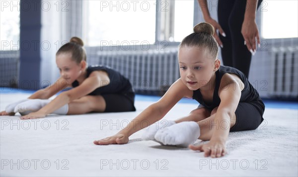 Training in the gym class. A group of children under the guidance of a coach perform exercises. Gymnastics concept. Mixed media