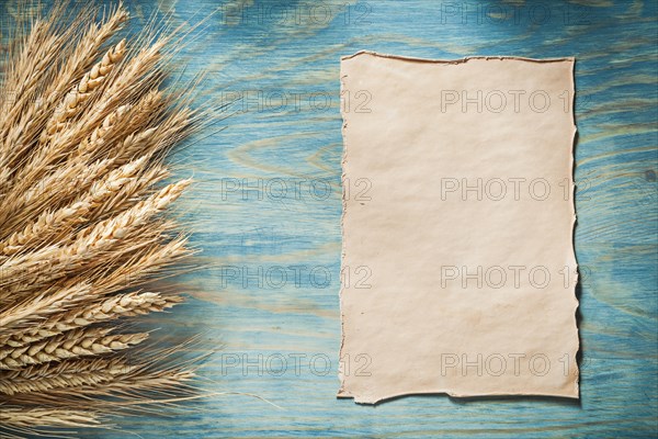 Bunch of rye ears vintage paper sheet on wooden board
