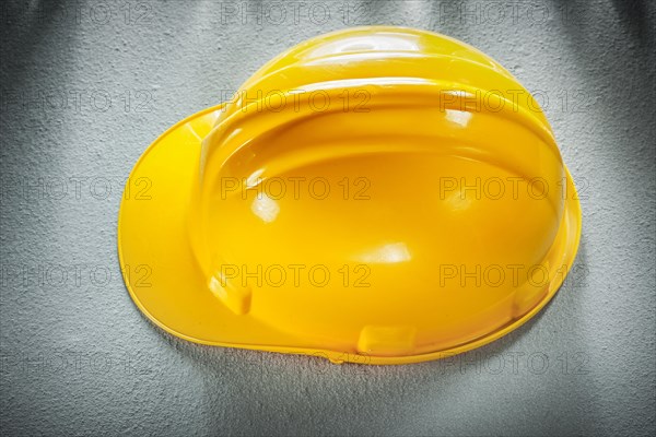 Yellow building helmet on concrete background top view