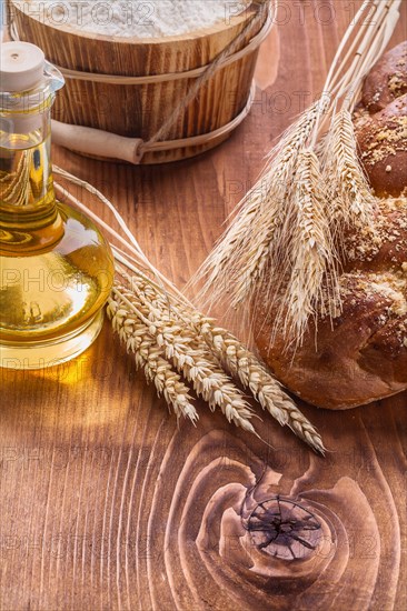 Food and drink concept ears of wheat loaf of sweet rolls bottle of oil bucket of flour on vintage boards