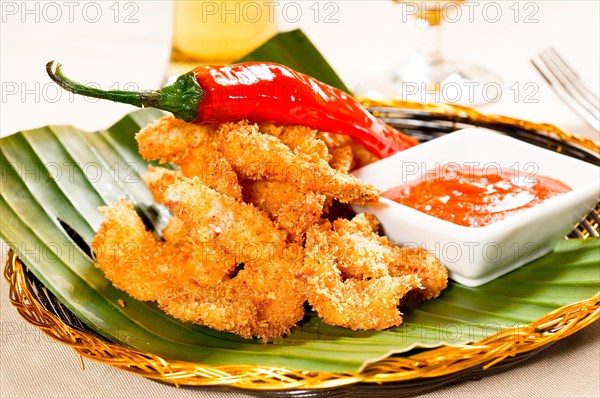 Fresh deep fried buffalo shrimps with a red chili pepper on top and sweet and sour sauce dip on side