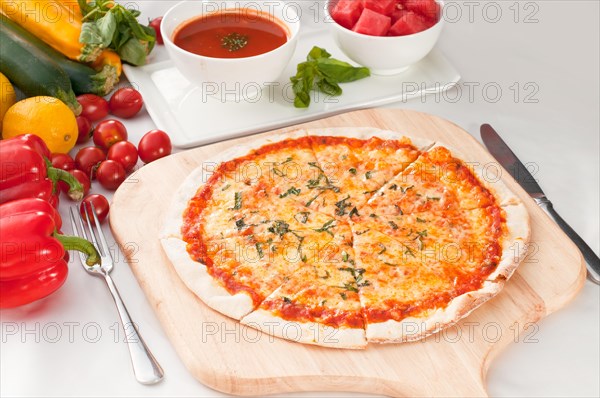 Italian original thin crust pizza Margherita with gazpacho soup and watermelon on side