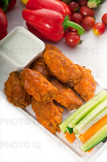 Classic buffalo chicken wings served with fresh pinzimonio and vegetables on background