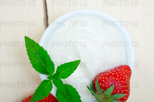 Organic Greek yogurt and strawberry over white rustic wood table