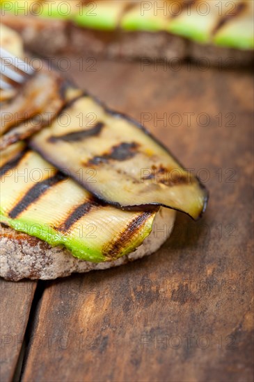 Grilled vegetables on rustic bread over wood table