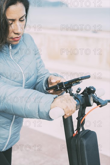Side view of Beautiful latin woman riding her motorized scooter in the city