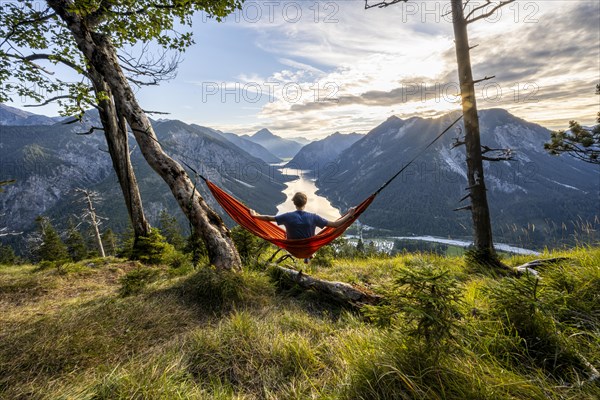 Young man sitting in an orange hammock