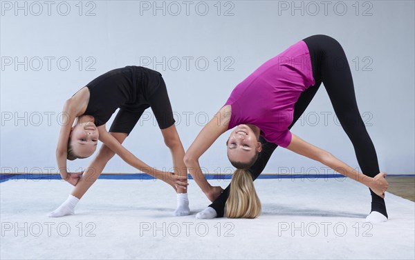 Training in the gym class. A little girl under the guidance of a trainer performs exercises. Gymnastics concept. Mixed media