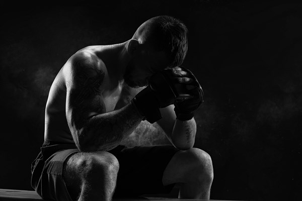 Kickboxer with overlays on his hands prays before the fight. The concept of mixed martial arts. MMA