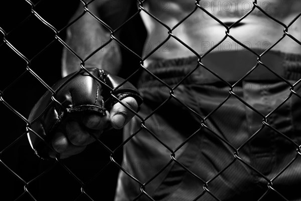 Black and white image of a man in a boxing cage. The concept of sports