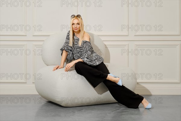 A fashionable woman sits in a soft chair