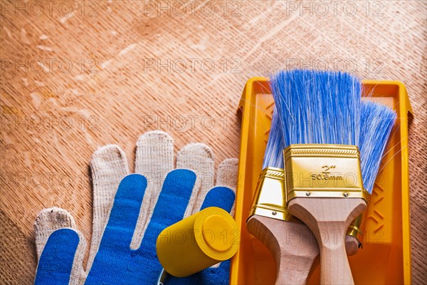 Paint roller Brush Tray and protective gloves on wooden board Maintenance concept