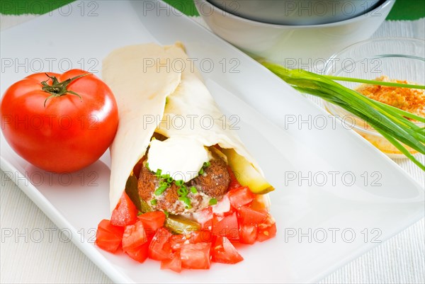 Fresh traditional falafel wrap on pita bread with fresh chopped tomatoes