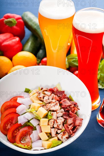 Fresh classic caesar salad with red and blonde beer on background