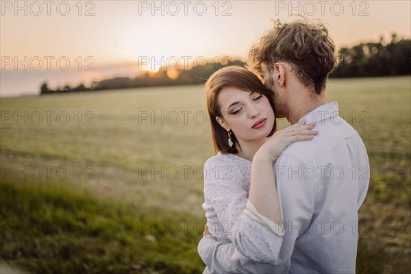 Couple in love in a field at sunset on a date in summer. Wedding engagement of a young couple