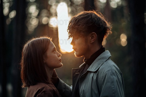 Beautiful fashionable couple in love in the forest at sunset in autumn