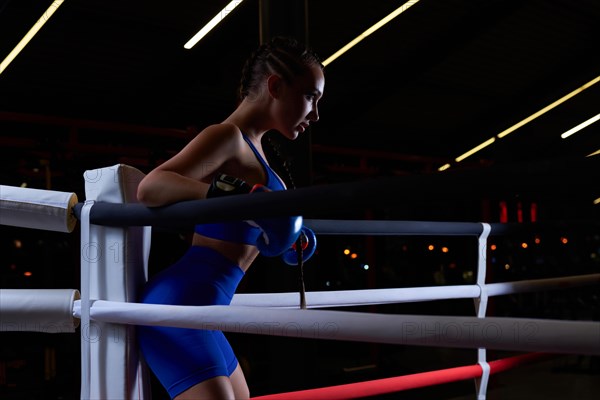 Powerful charged girl stands in the corner of the ring and is ready to explode in the next round. The concept of wrestling and boxing. Mixed media