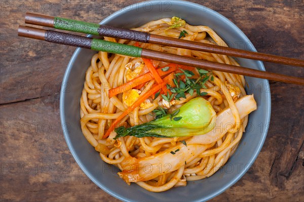 Hand pulled stretched Chinese ramen noodles on a bowl with chopstick