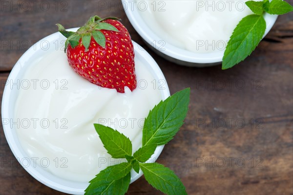 Organic Greek yogurt and strawberry on a rustic wood table