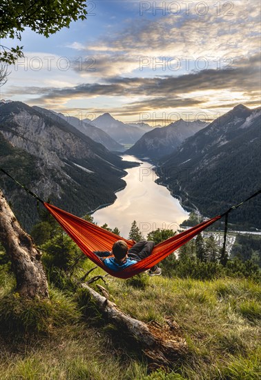 Young man sitting in an orange hammock