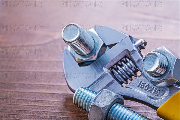 Adjustable key stainless threaded bolts and screw nuts on vintage wooden board construction concept